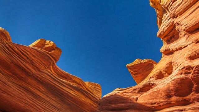 Sonnenbeschienene korallfarbene Sandsteinschlucht mit Blick in einen klaren blauen Himmel